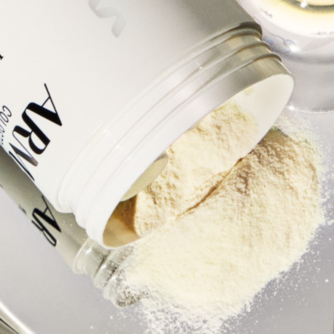 A jar of ARMRA colostrum spilling out onto a mirrored surface