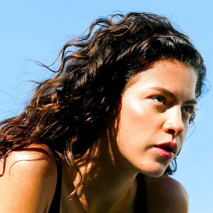 A woman with thick, curly brown hair looking away