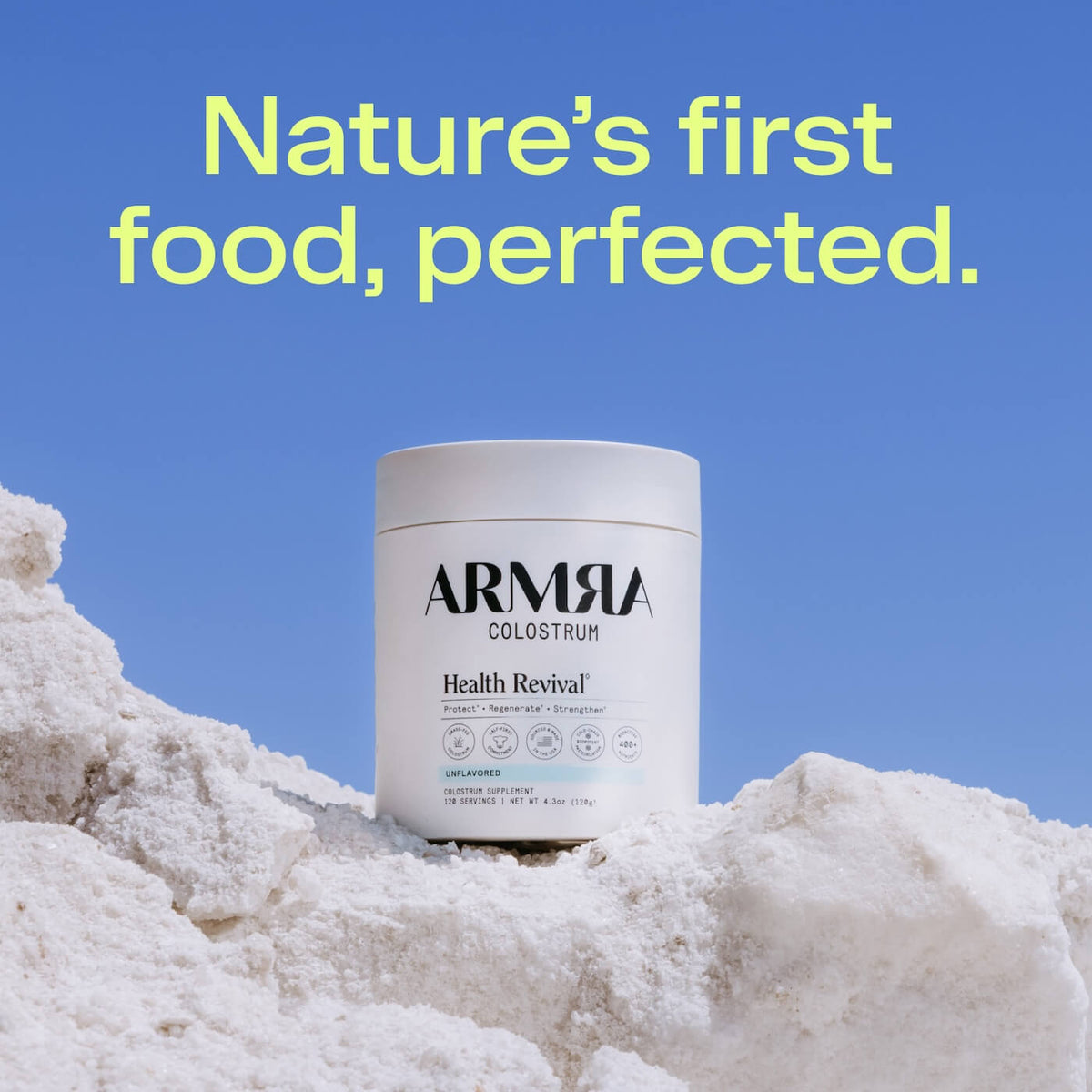 White ARMRA Colostrum jar labeled "Health Revival" and "Unflavored" positioned on white powder against blue background.