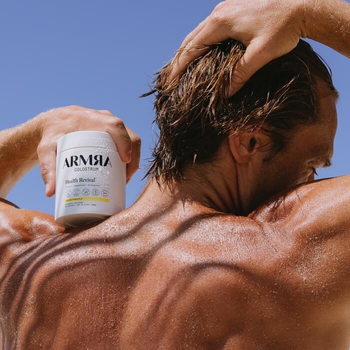 ARMRA colostrum Valera Pineapple resting on a muscular, tanned man's shoulder