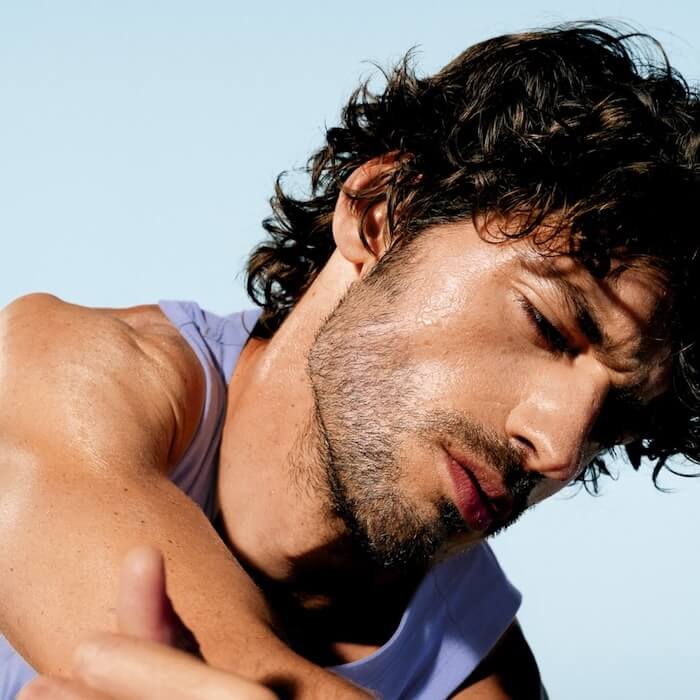 A man with curly brown hair and a light beard looking down
