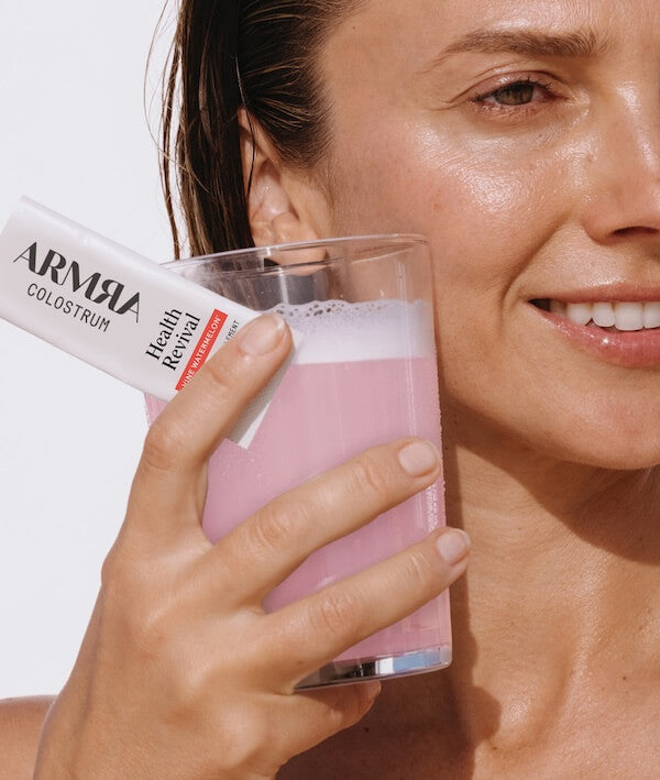 Woman holding a glass of ARMRA Colostrum