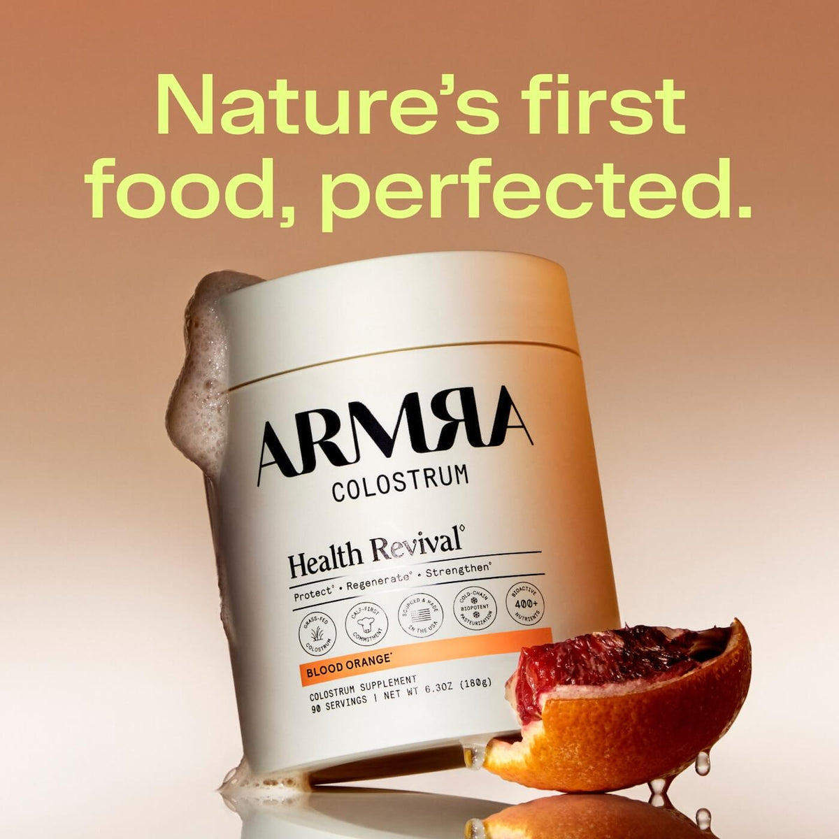ARMRA Colostrum jar with white and orange label beside blood orange slices on tan background.