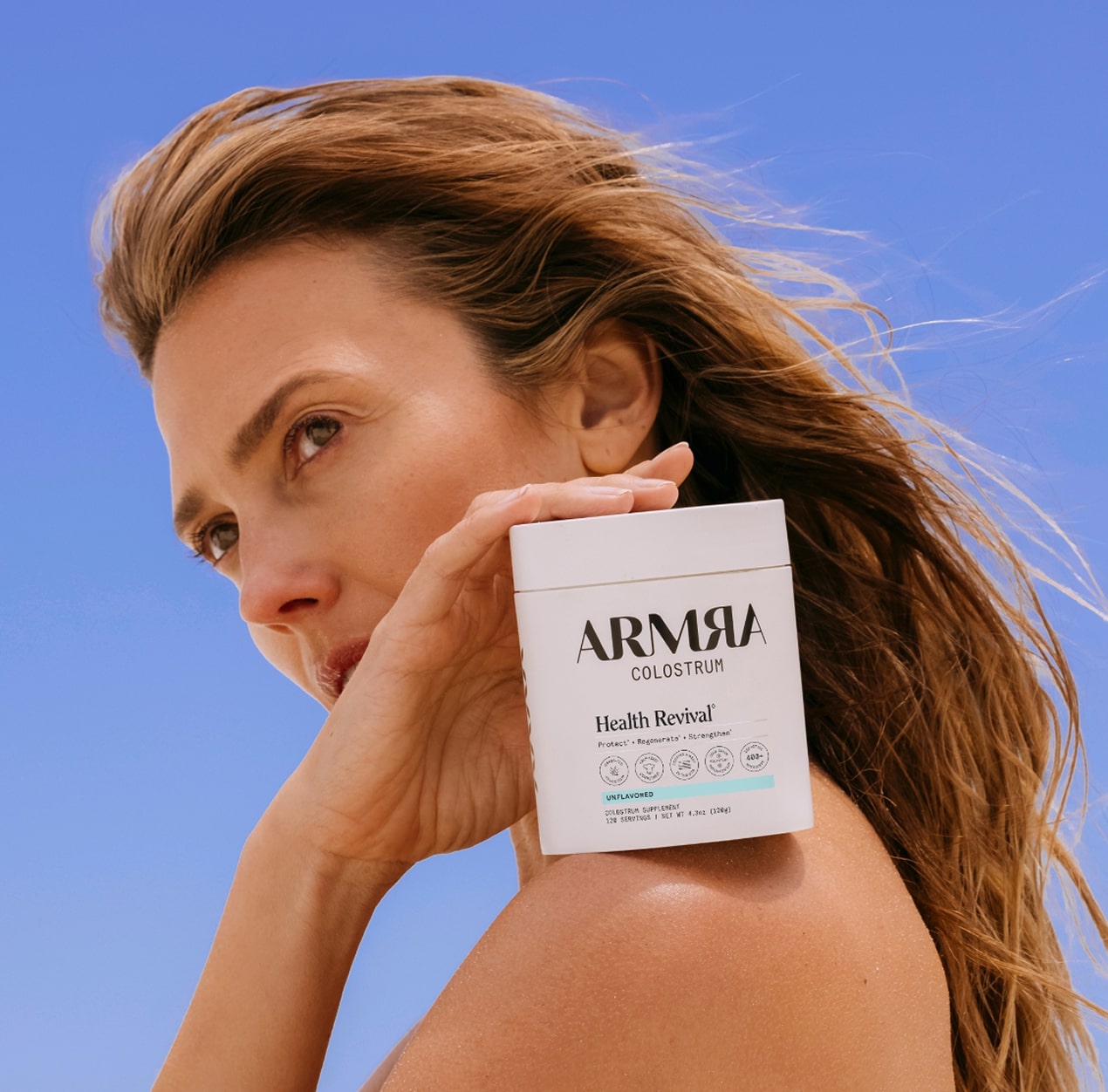 A woman holding a jar of ARMRA colostrum on her shoulder