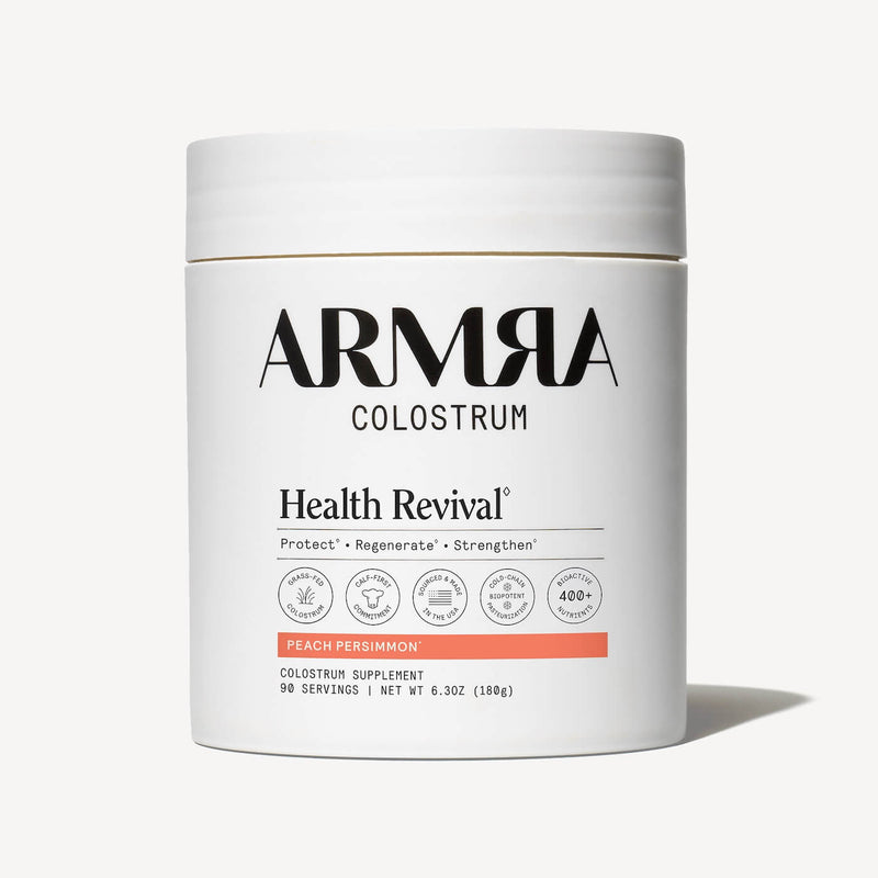 White cylindrical jar labeled ARMRA Colostrum with peach persimmon flavor band, 6.3oz net weight, 90 servings.