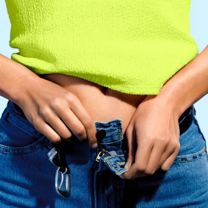 a woman buttoning up a pair of jeans 