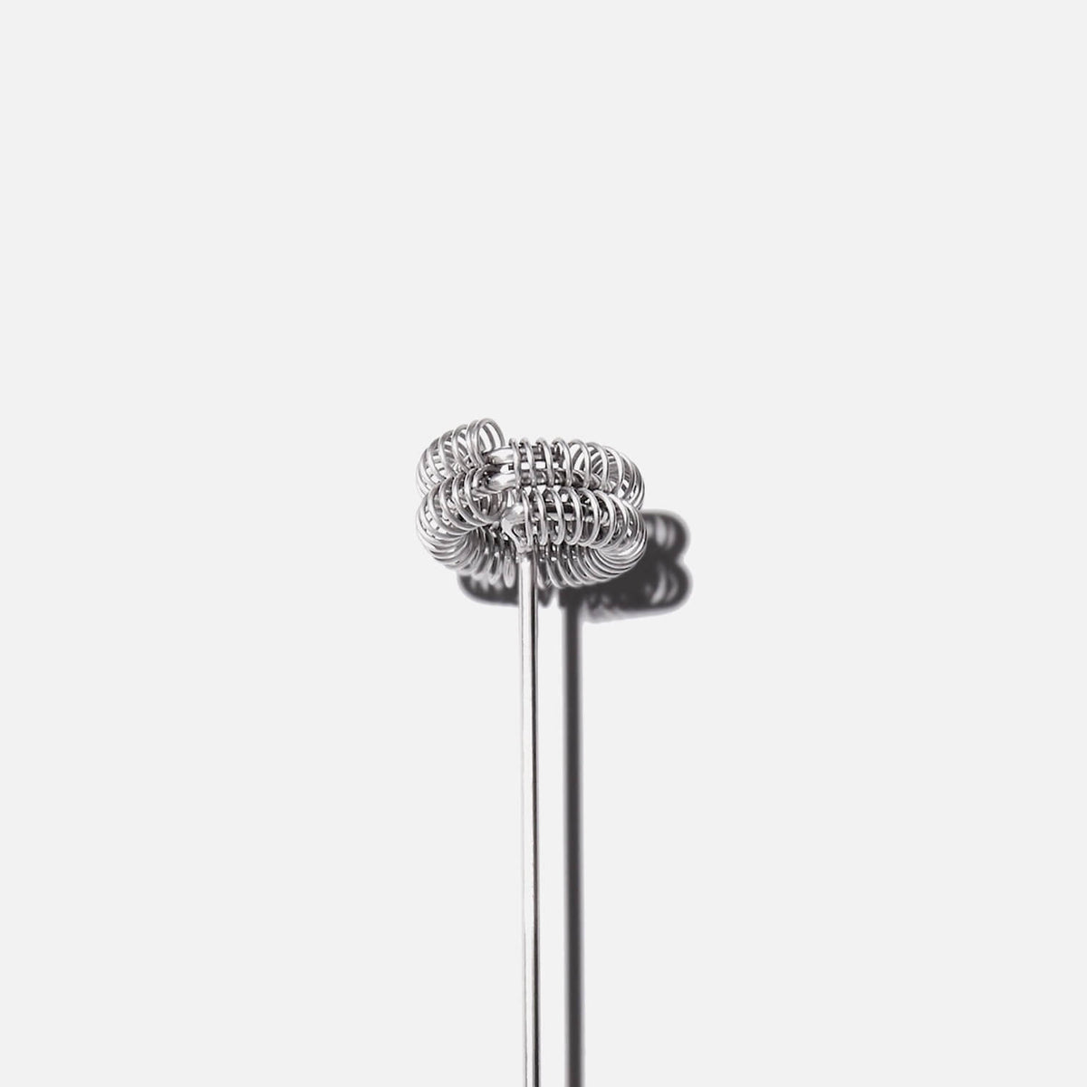 Silver whisk with spiral wire head and long thin handle on white background.