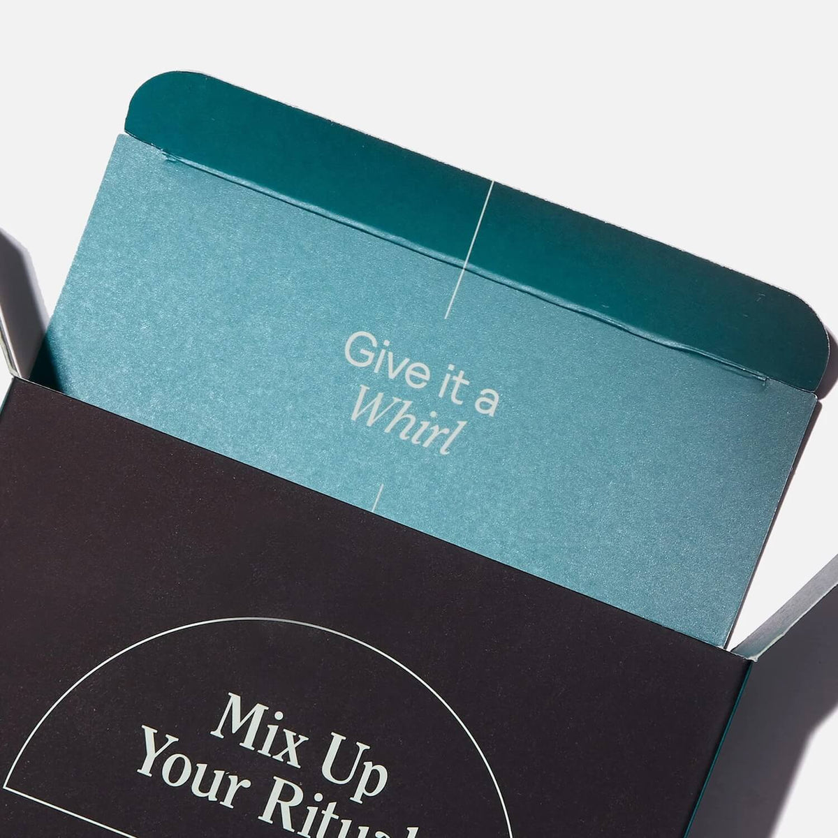 Teal and black product boxes stacked at an angle, with text reading "Give it a Whirl" and "Mix Up Your Ritual."